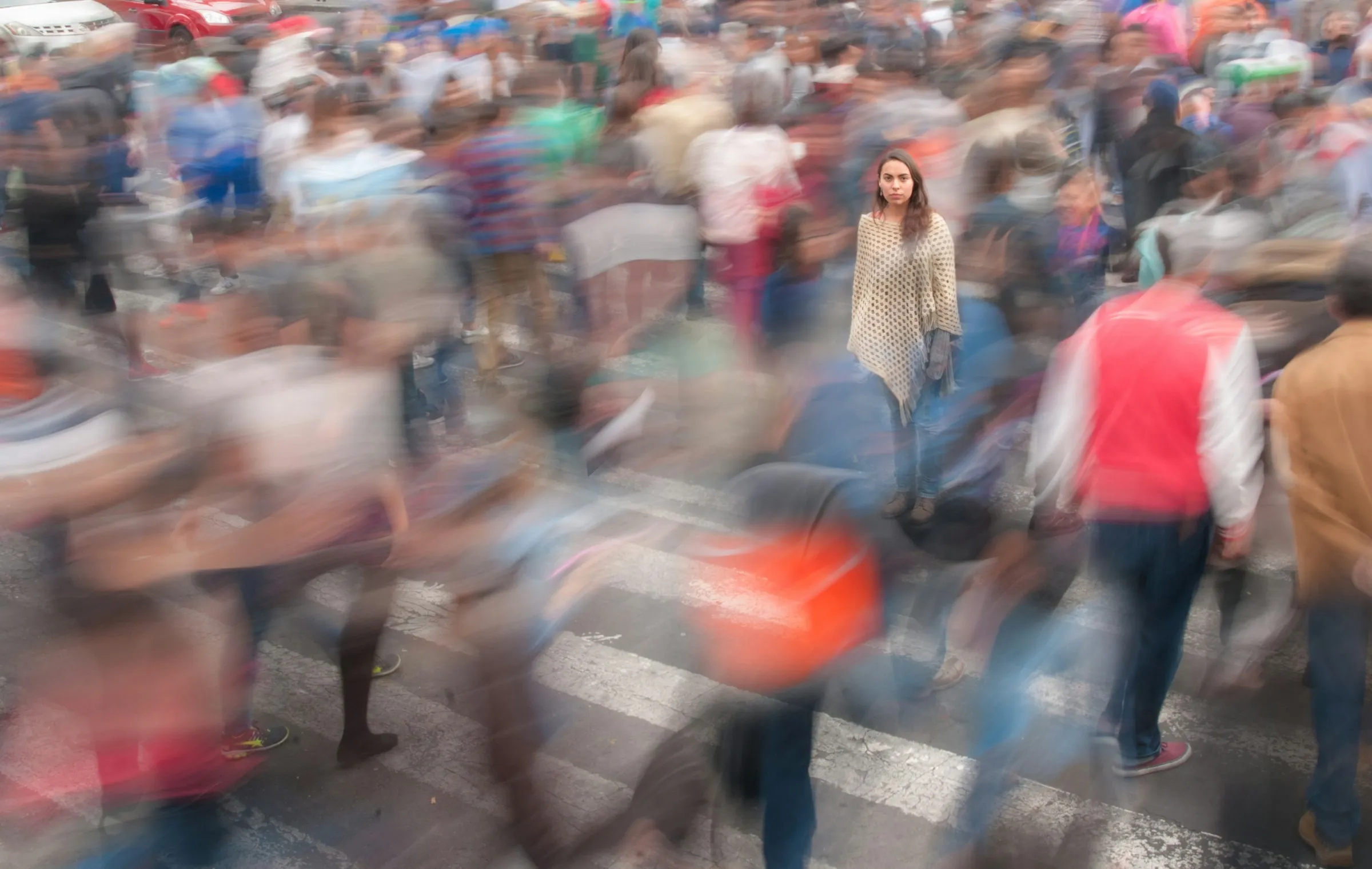 A woman standing still in a motion-blurred city crowd