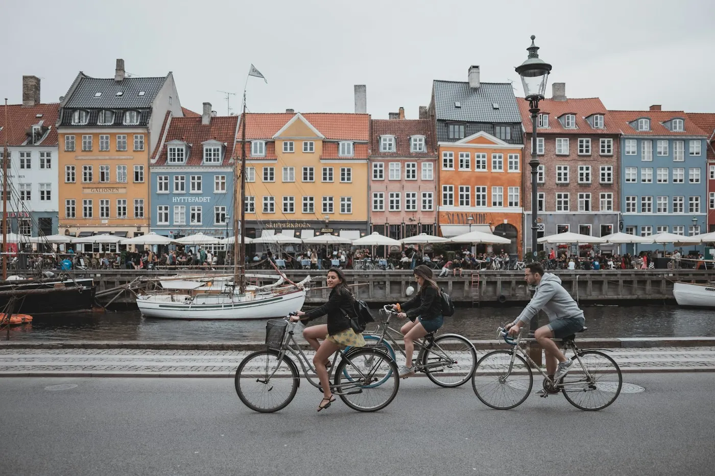Cyclists passing colourful canal houses in Copenhagen