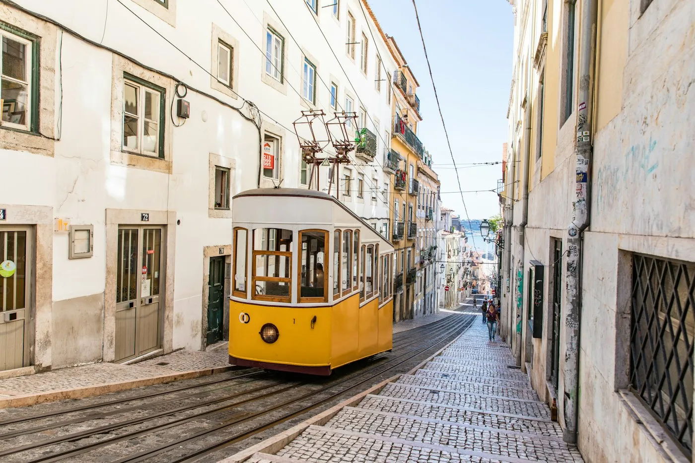 A yellow tram climbing a narrow Lisbon street